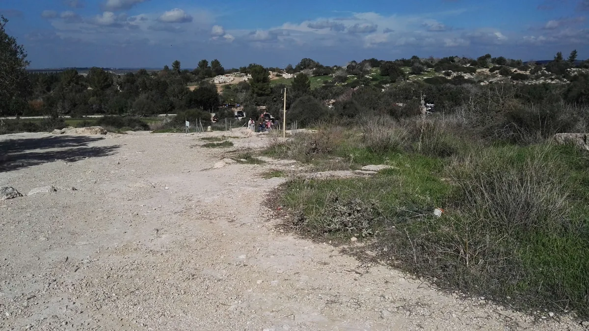 Gravel path through green scrub in Bet Guvrin-Maresha National Park, with visitors in the distance