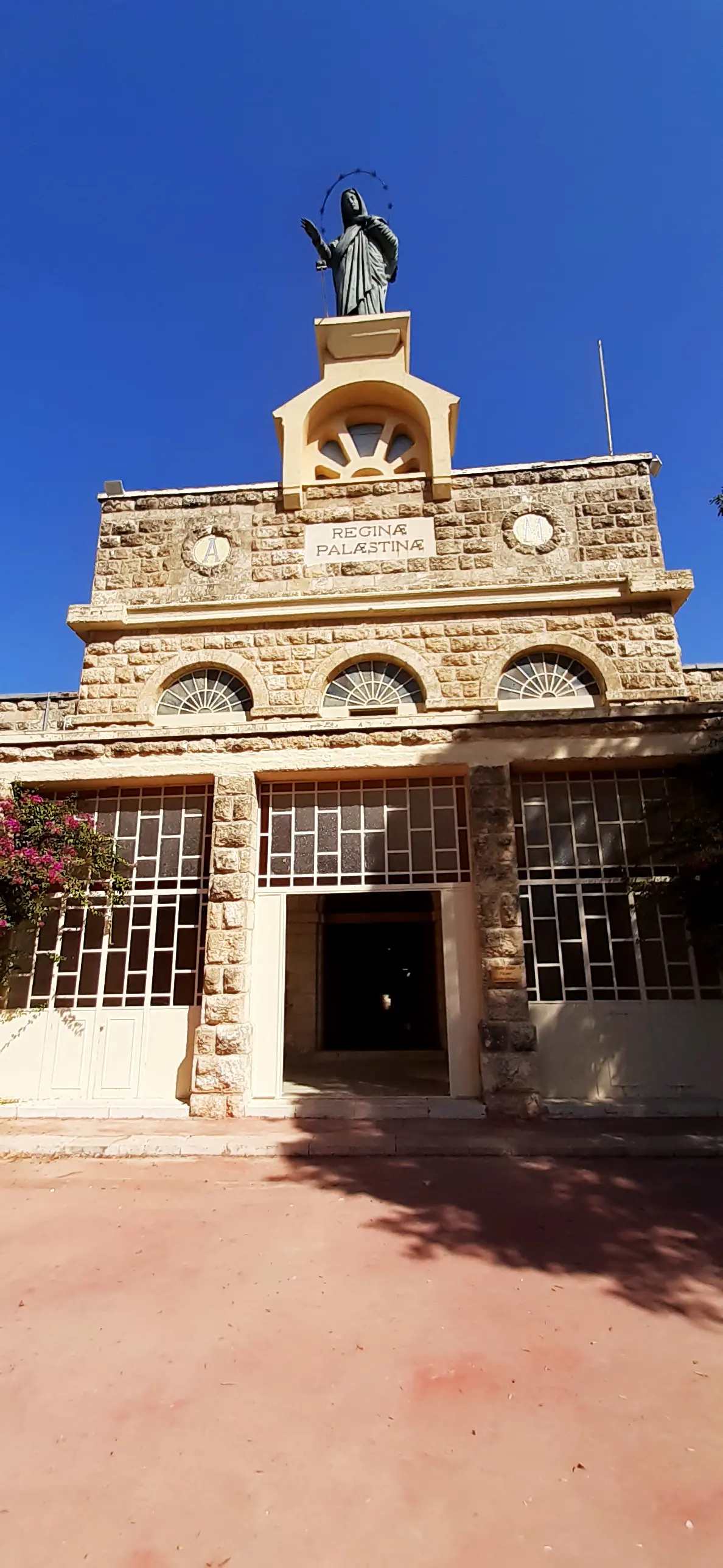 Facade of the Deir Rafat church with a statue of Mary on top and the inscription Reginae Palaestinae