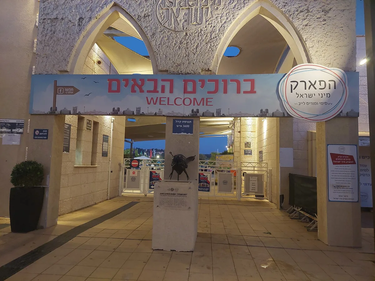Entrance gate of Mini Israel at dusk, with a welcome banner in Hebrew and English